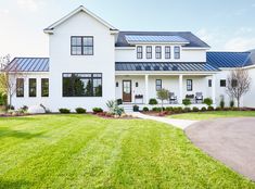 a large white house with lots of windows on it's front porch and lawn