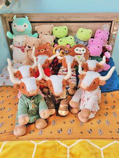 a bunch of stuffed animals sitting on top of a bed next to eachother