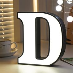 the illuminated letter d sits next to a coffee cup