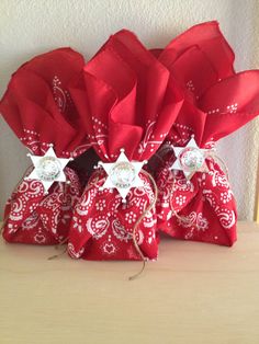 three red bags with white stars on them sitting on top of a wooden table next to a wall