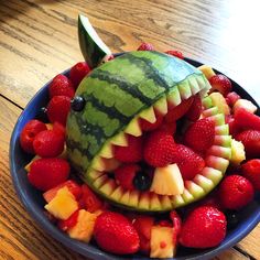 a bowl filled with fruit that includes watermelon, raspberries and pineapples