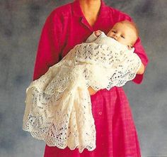 a woman holding a baby in a white crochet wrap on top of her chest