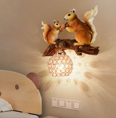 two squirrels are sitting on top of a light fixture in a child's room