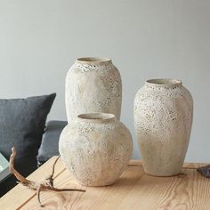 three white vases sitting on top of a wooden table