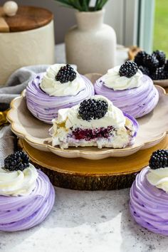 several desserts are arranged on plates with blackberries and cream frosting in the middle