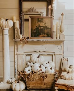 white pumpkins are stacked in a wooden crate next to a painting on the wall