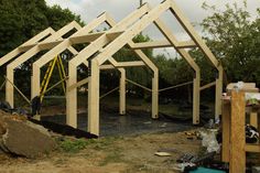 an unfinished house being built in the middle of a field with trees and other construction materials