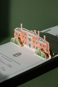 an open book with a paper cut out of the front and side of a building