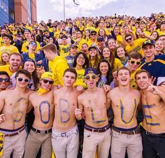 a group of young people standing next to each other in front of a crowd with numbers painted on their shirts