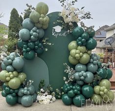 a large green and white balloon arch with flowers