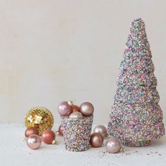 three small christmas trees are next to each other with balls on the ground in front of them