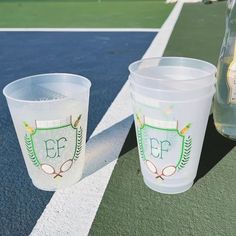 two plastic cups sitting on top of a tennis court