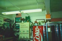 a coca - cola sign is hanging from the ceiling in an office with posters on the wall