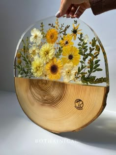 a person holding a glass plate with flowers on it and the bottom half is covered in wood