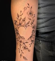 a woman's arm with flowers and a heart tattoo on the left side of her arm