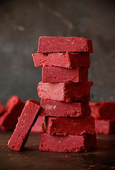 a stack of red brick sitting on top of a wooden table next to a knife