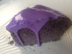 a close up of a piece of cake on a plate with purple icing drizzled