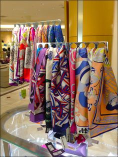 many colorful scarves are hanging in a store