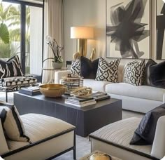 a living room filled with lots of white furniture and black and white pillows on top of couches