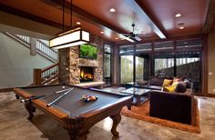 a pool table in the middle of a living room with couches and a fireplace