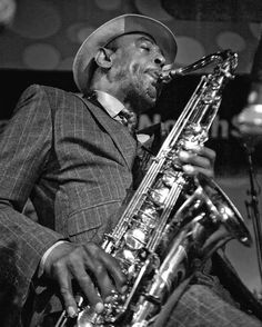 a man in a suit and hat playing a saxophone