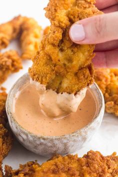 a person dipping sauce on some fried food in a small bowl with the words copycat raising cane's sauce