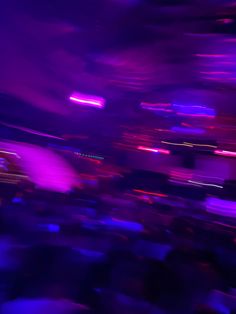 blurry image of people in an audience at a concert with purple and blue lighting