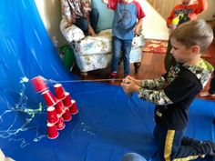 a group of young boys playing with an inflatable ball and stick game on a blue tarp covered floor