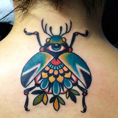 the back of a woman's neck with a colorful beetle tattoo design on it