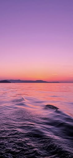 the sun is setting over the water and it looks like waves are coming in to shore