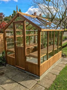 a small wooden greenhouse in the middle of a yard