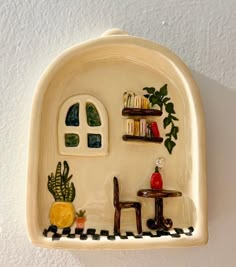 a ceramic shelf with books and plants on it's sides, in the shape of a house