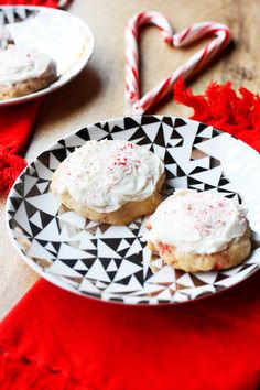 two cookies with white frosting and candy canes on a plate next to a heart shaped peppermint