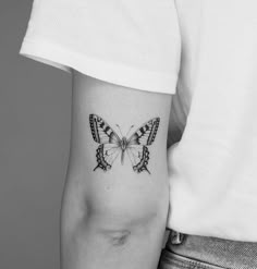 a black and white photo of a butterfly tattoo on the left inner arm, showing its wings