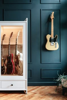 an electric guitar case in front of a wall with guitars hanging on it's sides