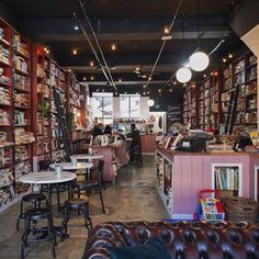 the inside of a book store with many books on shelves and leather couches in front of it