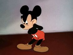 a cartoon mickey mouse standing in front of a wall