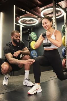 a man and woman doing squats in the gym