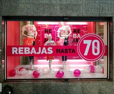 a store window with mannequins dressed in pink and white shirts on display