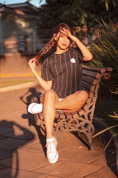 a woman sitting on a bench with her hair in the air and wearing tennis shoes