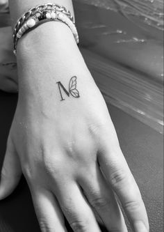 a woman's hand with a butterfly tattoo on her left wrist and the letter n