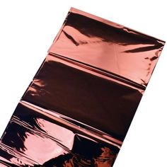 a piece of shiny metal foil on top of a white surface with black and pink stripes