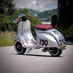 a scooter is parked on the side of the road in front of some bushes