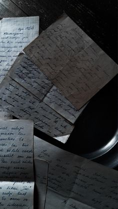 several pieces of paper on top of a table with papers scattered about it and one piece of black plate in the middle