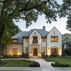 a large white house with lots of windows and lights on it's front door