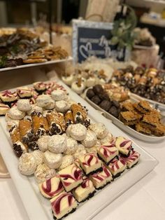 various desserts are displayed on trays at a buffet