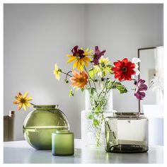 three vases with flowers in them sitting on a table next to a candle holder