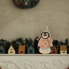 there is a penguin sitting on top of the mantel with christmas decorations around it