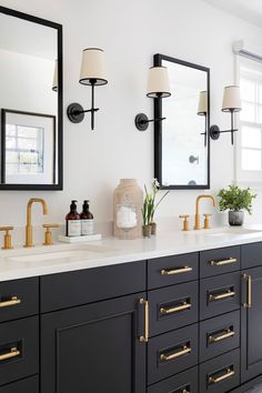 a bathroom with two sinks, mirrors and lights on the wall above them is decorated in black and gold