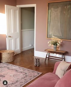 a living room filled with furniture and a painting hanging on the wall above a doorway